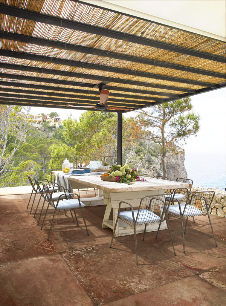 Terrasse extérieure avec table à manger, sol en grès cérame effet terre cuite rouge.
