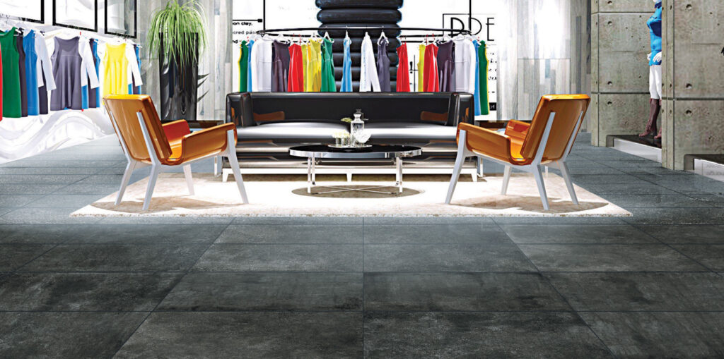 Magasin de vêtements avec des chaises et un canapé, sol en grès noir effet béton.