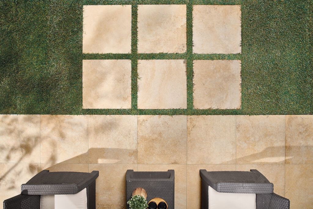 Vue plongeante d'un jardin aménagé avec pose de carreaux en grès cérame effet pierre sur gazon