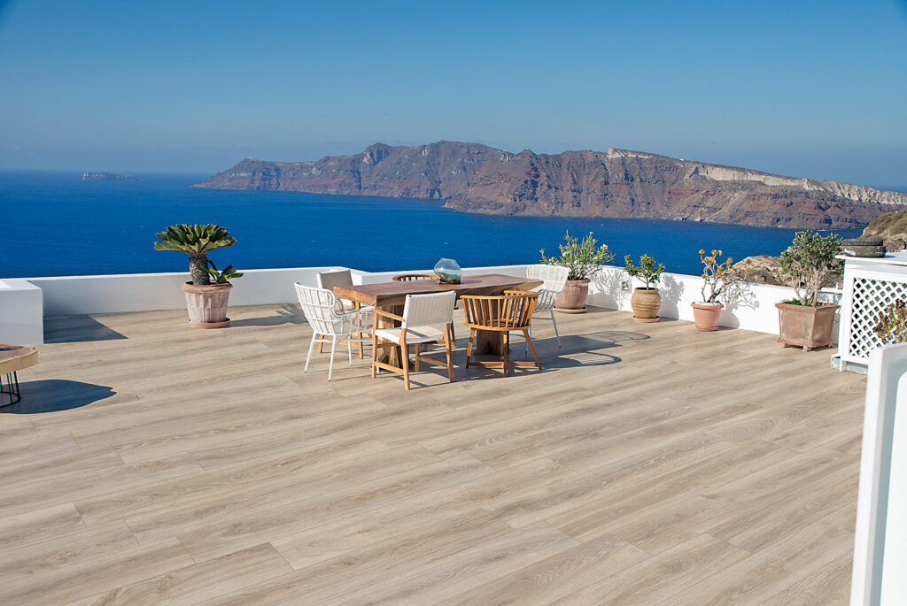 Terrasse en bord de mer avec table à manger, sol en grès cérame effet bois.