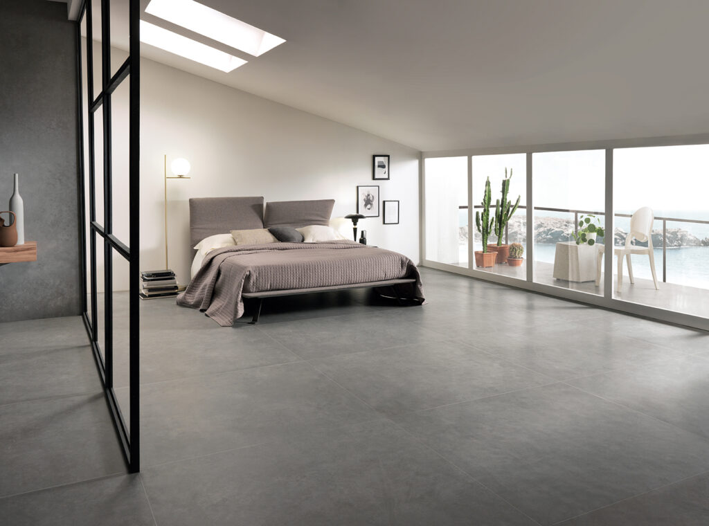 camera da letto con letto e balconcino, pavimento in gres effetto cemento