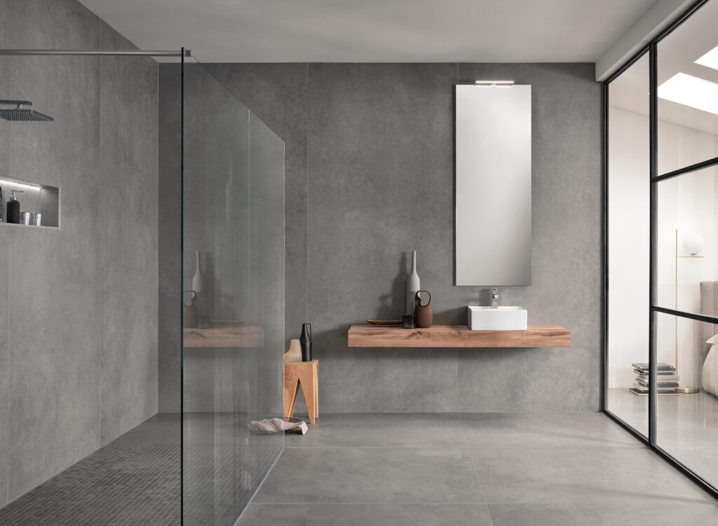 Hauptbadezimmer mit Dusche und Waschtisch, verkleidet mit Feinsteinzeug in Betonoptik.