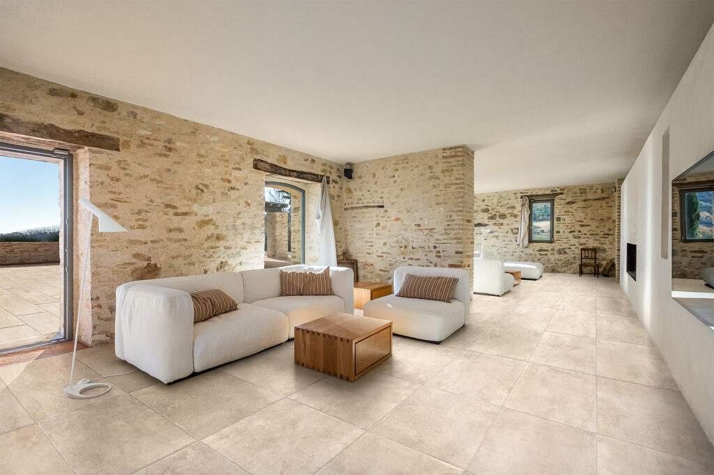 Rustikales Wohnzimmer mit Steinwänden und beigem Steinoptik-Boden.