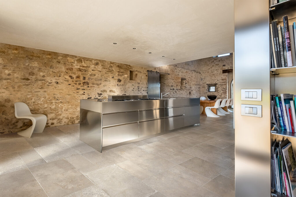 Küche mit Steinwand und Feinsteinzeugboden in Steinoptik.