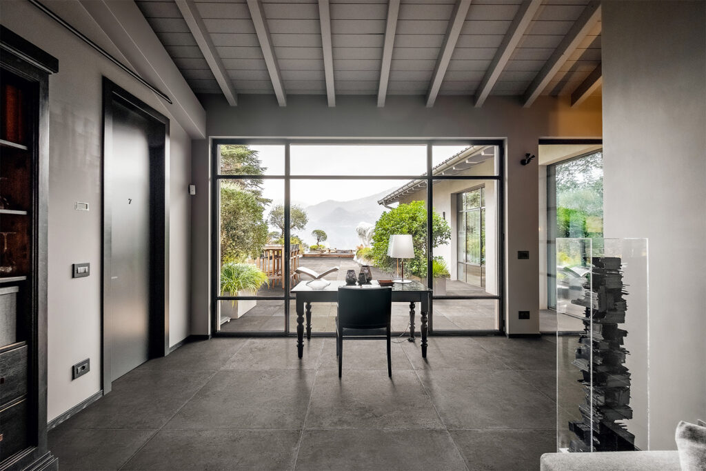 Studio mit Glasfront und dunkelgrauem Feinsteinzeugboden in Steinoptik.