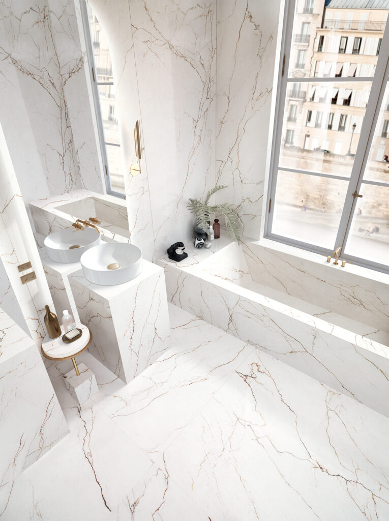 Détail de la baignoire et du lavabo recouverts de grès cérame effet marbre avec des veines caramel