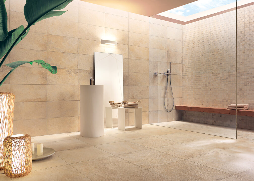 Salle de bain avec douche à l'italienne entièrement revêtue en grès cérame effet pierre. La paroi de douche est agrémentée d'une mosaïque