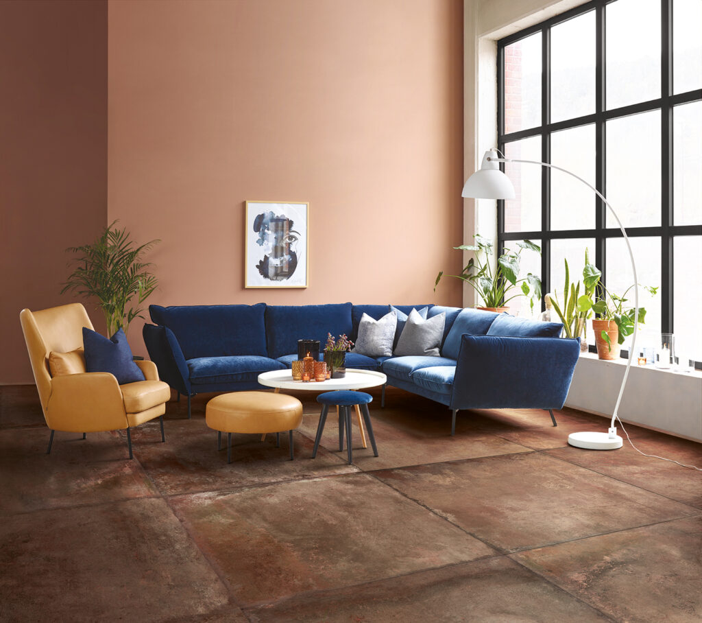 living con gres effetto cotto rosso, divano blu e elementi d'arredo