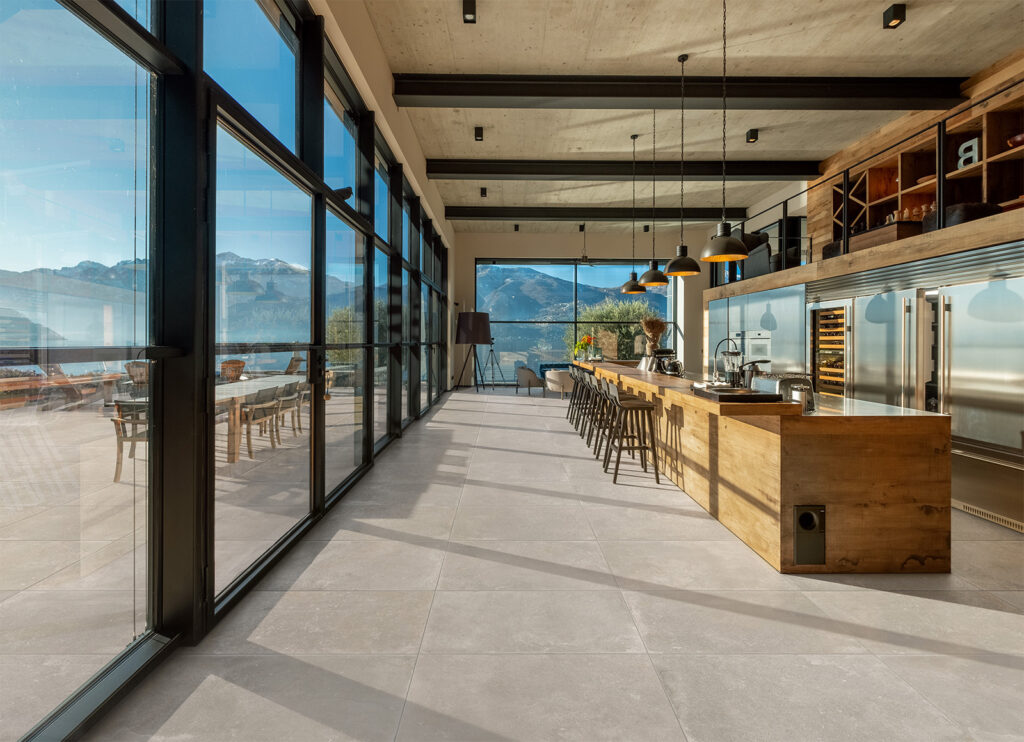 cucina con isola, pavimento in gres effetto pietra grigio in continuità con l'outdoor