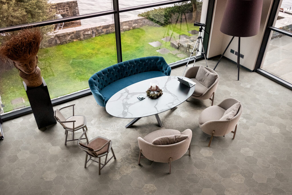 Espace de vie avec table et assises, sol en carreaux hexagonaux effet pierre