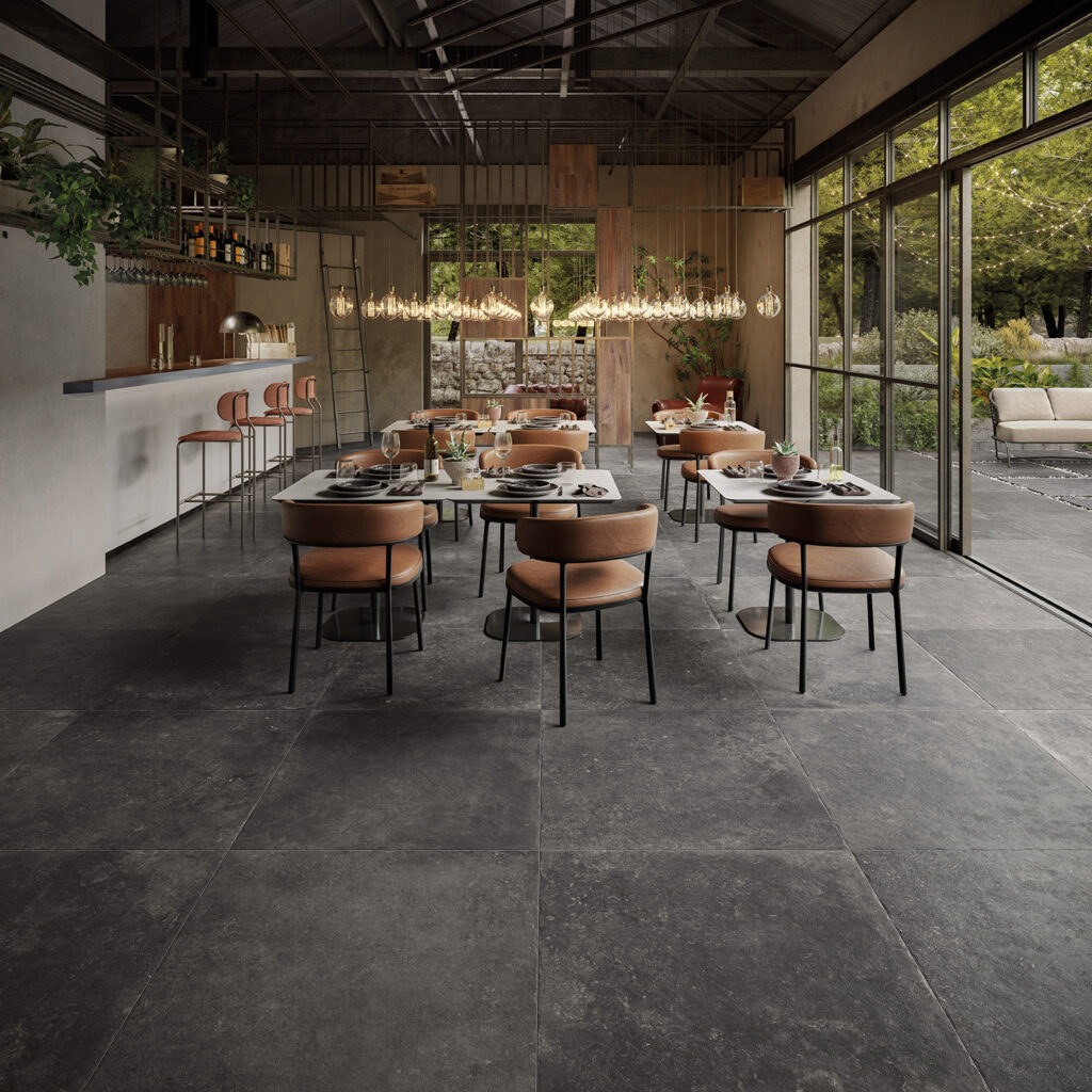 Restaurant avec tables aménagées et sol en grès cérame effet pierre noir/gris