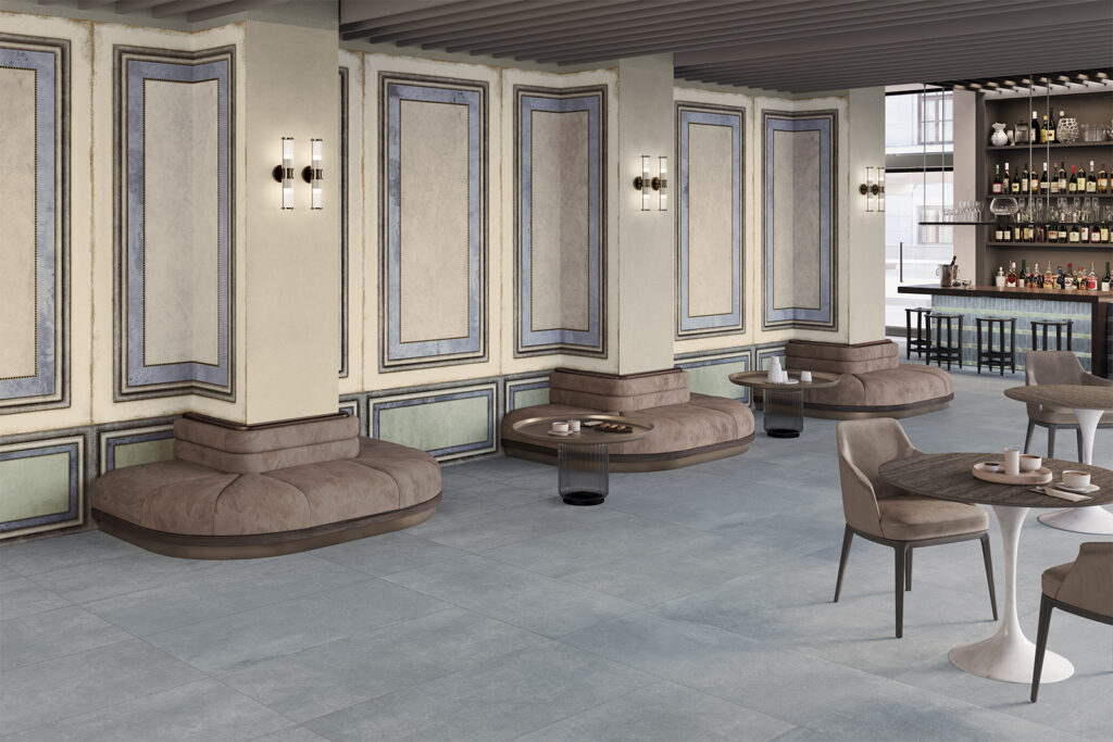bar con divani e tavolini marroni, pavimento e rivestimento in gres effetto cemento