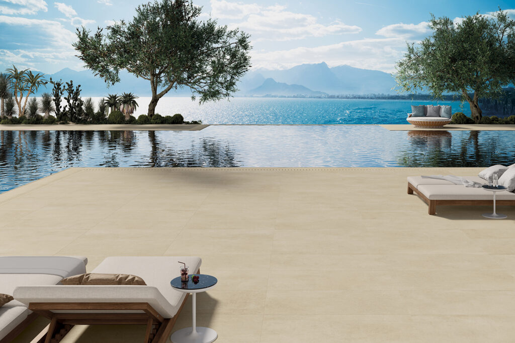 piscina a sfioro con lettini, vista lago rivestita in gres effetto cemento beige