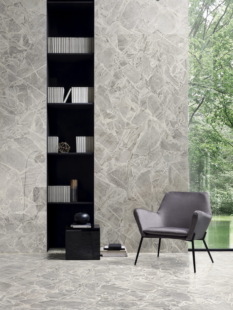 Living con libreria a parete e rivestimento in gres effetto marmo grigio cenere con cristalli
